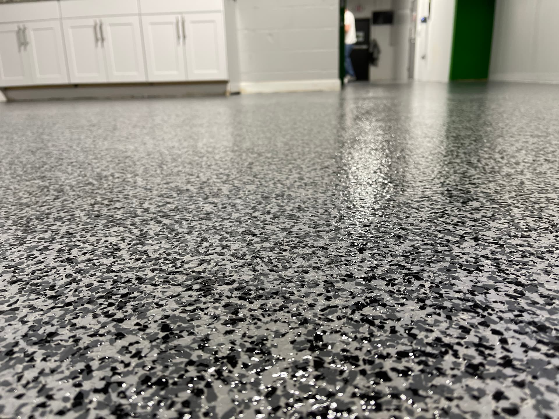 Grey and black flake floor with cabinets in the background