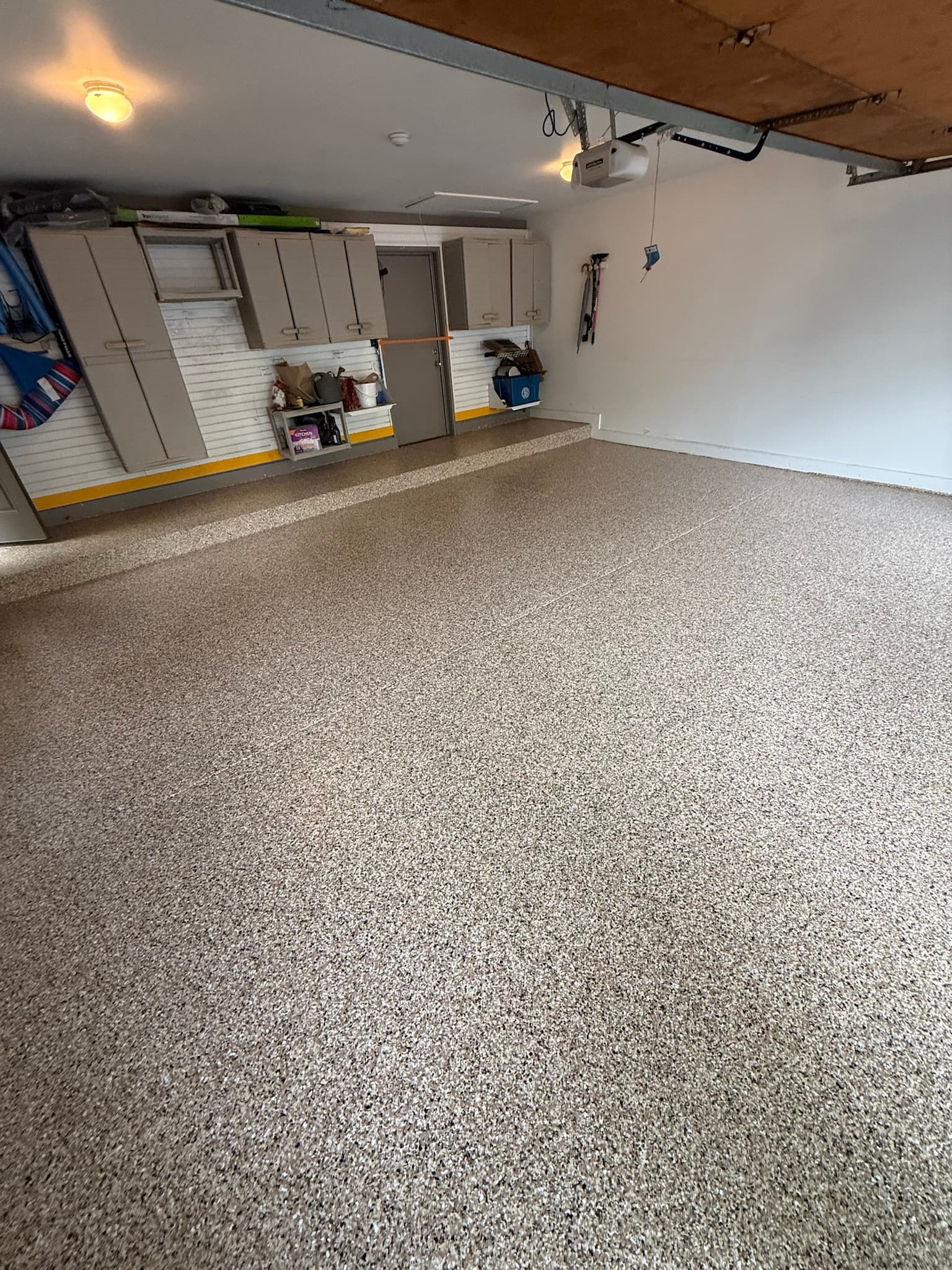 Tan flake garage floor with cabinets, angled view
